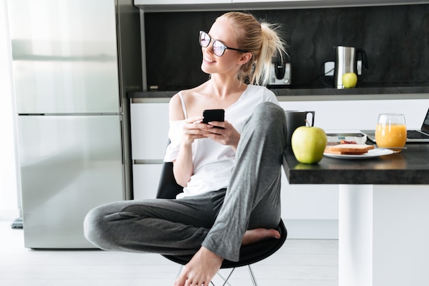 Young attractive lady looking aside while using smartphone