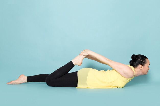 Young attractive lady in yellow shirt and black trousers doing yoga postures