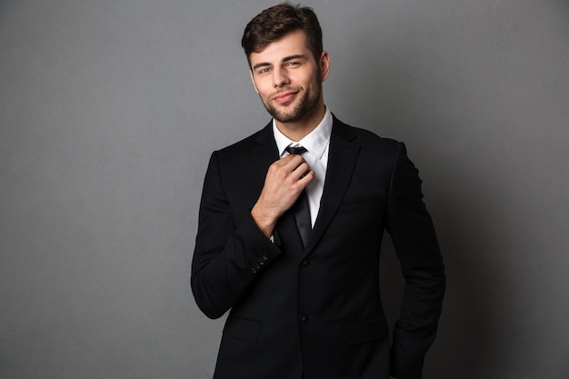 Young attractive man in classic suit straightens his tie, 