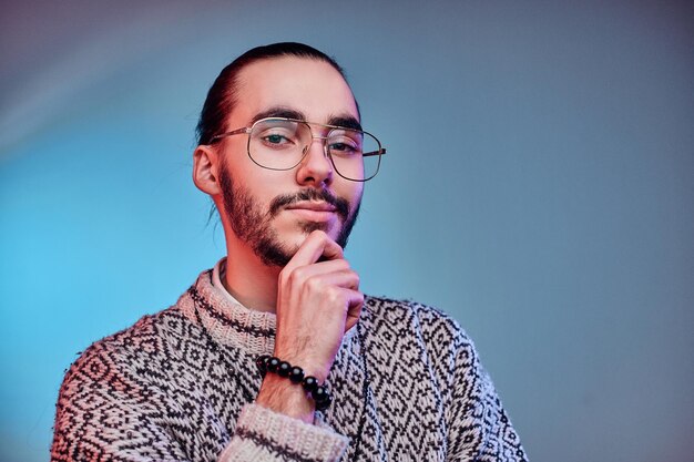 Young attractive man in glasses is posing for photographer at studio.