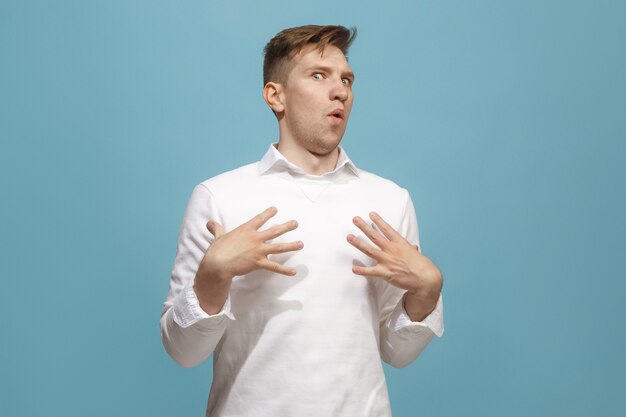 The young attractive man looking suprised isolated on blue