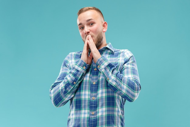 The young attractive man looking suprised isolated on blue