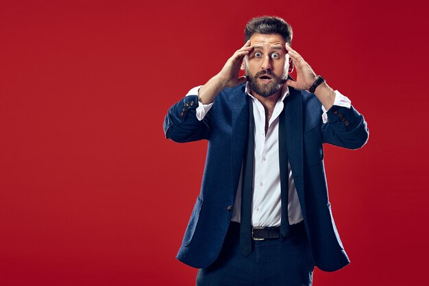  young attractive man looking suprised isolated on red