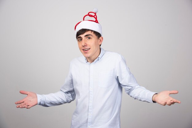 クリスマスの帽子に立ってカメラを見ている若い魅力的な男性モデル