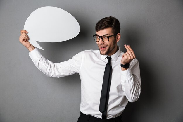 Young attractive man in white shirt holding empty message bubble, 