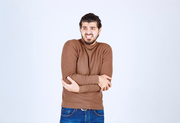 young attractive model in brown sweater doing gestures over white wall.