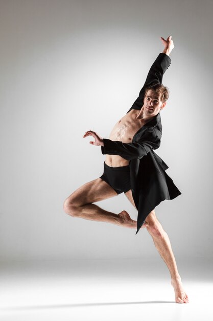 The young attractive modern ballet dancer on white wall