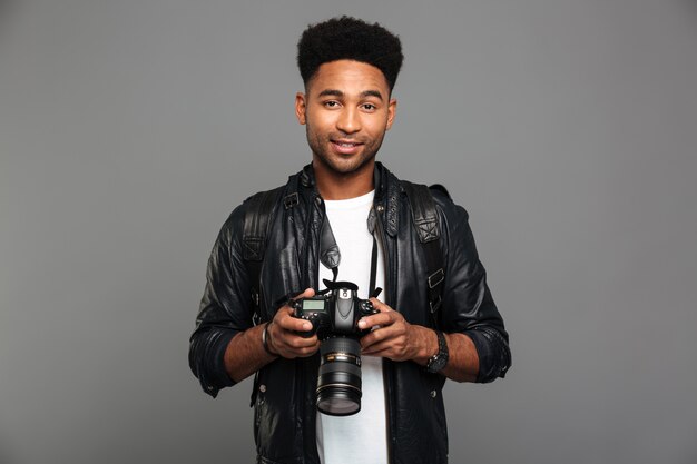 Young attractive smiling afro american man holding digital camera, looking