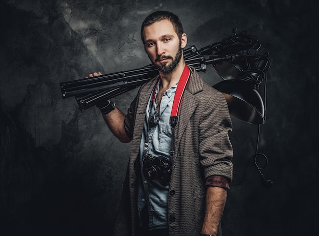 Young attractive student is carrying special lamp while posing for photographer.