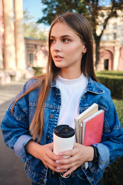 Foto gratuita giovane attraente studentessa alla moda in giacca di jeans distoglie lo sguardo pensieroso all'aperto