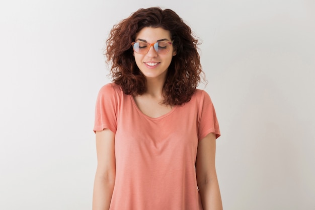 Young attractive stylish woman in glasses with closed eyes, thinking, dreamimg, curly hair, smiling, positive emotion, happy, isolated, pink t-shirt, student