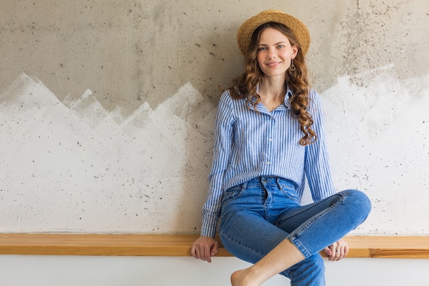 Young attractive stylish woman sitting at wall