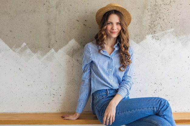 Young attractive stylish woman sitting at wall