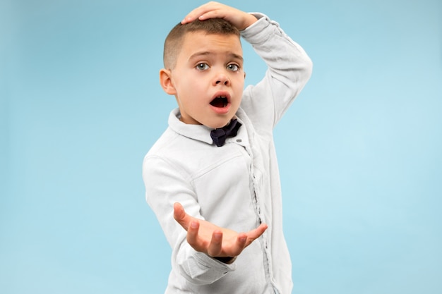 The young attractive teen boy looking suprised isolated on blue