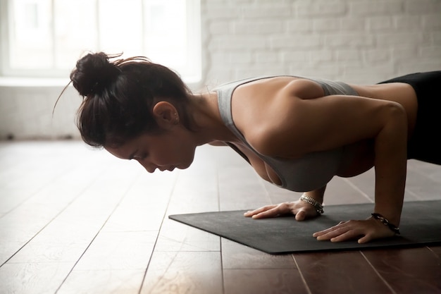 Chaturanga dandasanaポーズ、ロフトスタジオの若い魅力的な女性