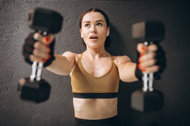 Foto gratuita giovane donna attraente che si esercita con le teste di legno alla palestra