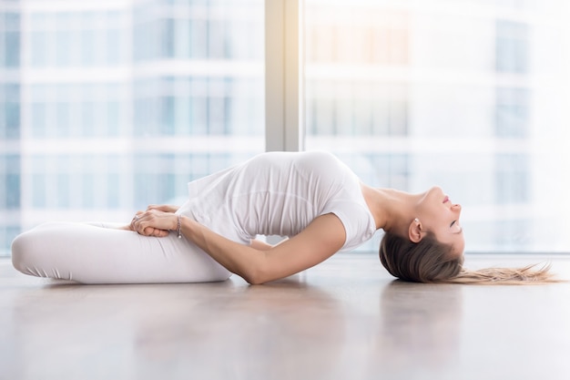 Free photo young attractive woman in fish pose against floor window