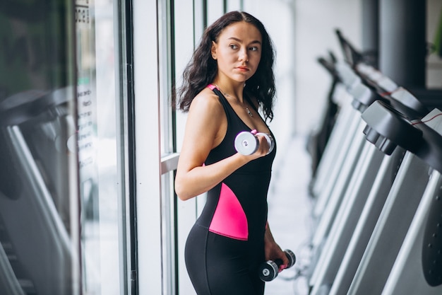 Young attractive woman at the gym with dumbbells