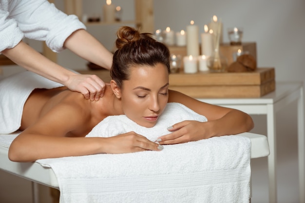 Young attractive woman having massage relaxing in spa salon.