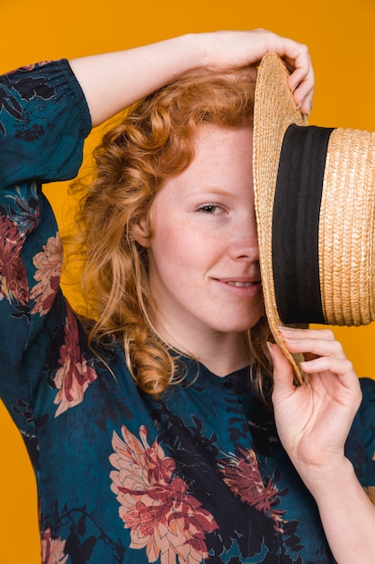 Free photo young attractive woman hiding half of face with hat