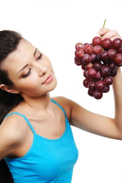 Giovane donna attraente che tiene un grappolo d'uva