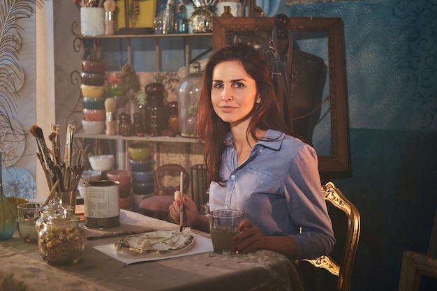 Young attractive woman is making a beautiful decorative plate at her workshop.