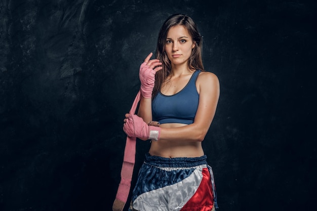 La giovane donna attraente indossa bende speciali per le mani prima dell'allenamento di boxe.