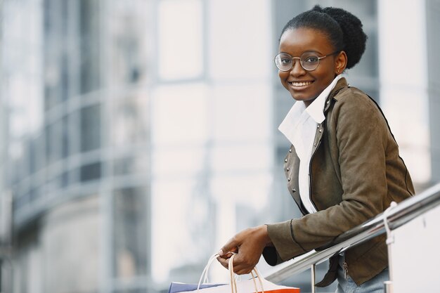 Young attractive woman in jacket and holding lot of shopping packages and walking along street. Shopping concept