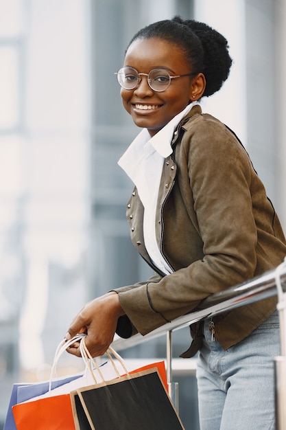 Young attractive woman in jacket and holding lot of shopping packages and walking along street. Shopping concept