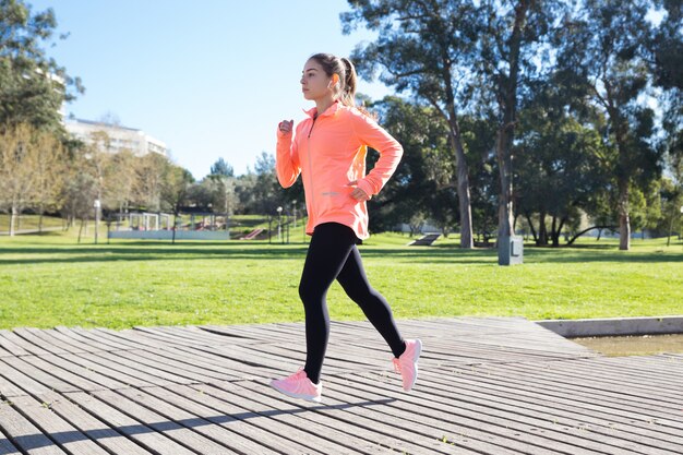 Young attractive woman jogging in city park