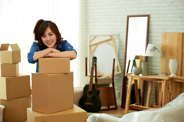 Young attractive woman leaning on a pile of package boxes smiling