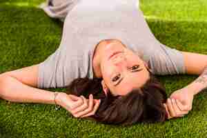 Free photo young attractive woman lying on lawn