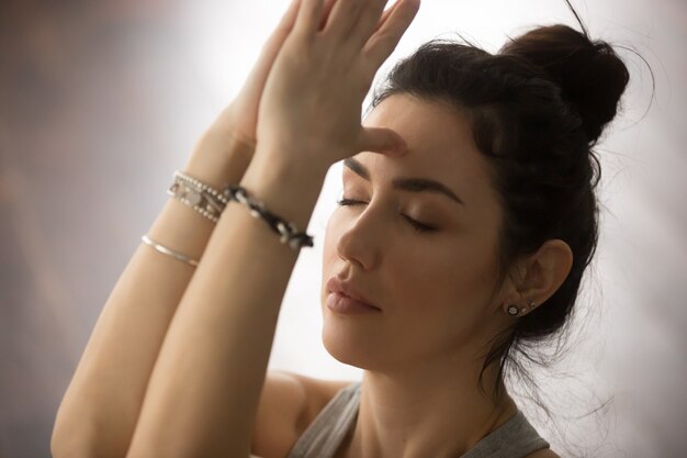 Young attractive woman making namaste with closed eyes