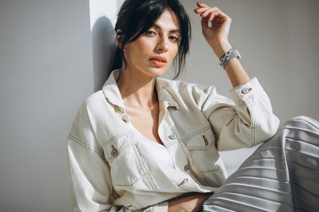 Young attractive woman model sitting by the wall