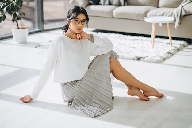 Free photo young attractive woman model sitting on floor at the living room