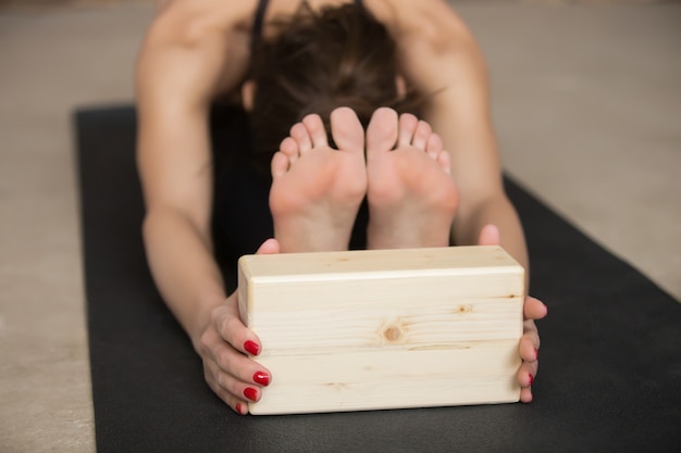 Foto gratuita la giovane donna attraente in paschimottanasana posa con il blocco, gre