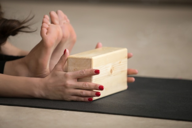 Free photo young attractive woman in paschimottanasana pose with block, stu