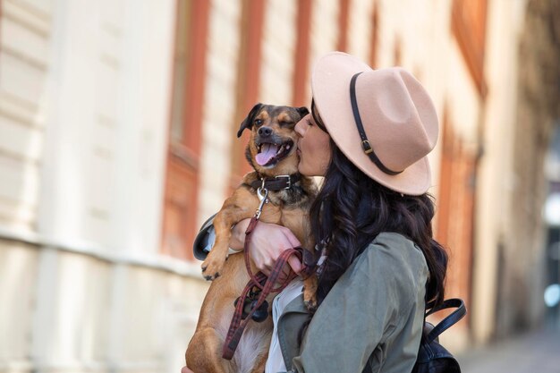 街のストリートライフスタイルの人々の概念で彼女の犬と遊ぶ若い魅力的な女性屋外で遊ぶ彼女の犬と美しい女性