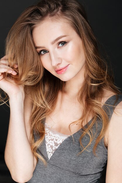 Young attractive woman posing over dark wall