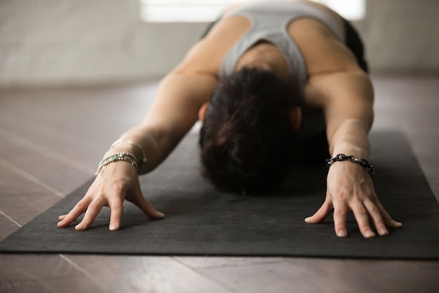 Foto gratuita yoga di pratica della giovane donna attraente posa del bambino