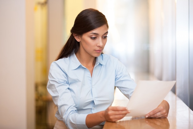 Young Attractive Woman Reading Document in Cafe