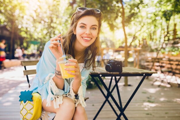 Молодая привлекательная женщина, сидящая в кафе в летнем модном наряде