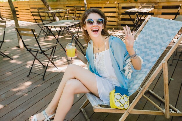 여름 패션 복장, 흰 드레스, 파란 망토, 선글라스, 미소, 레모네이드, 세련된 액세서리를 마시고 휴가에 편안한 갑판 의자에 앉아 젊은 매력적인 여자