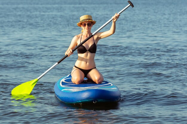 Young attractive woman sitting on paddle board