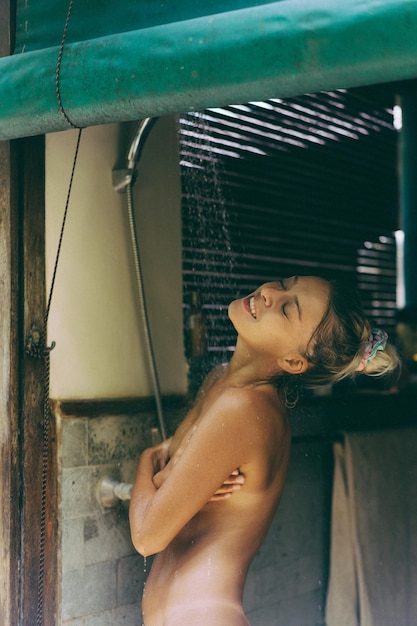 Young attractive woman takes a shower in a tropical location