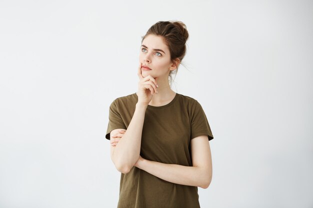 Young attractive woman thinking with hand on chin looking to distance.