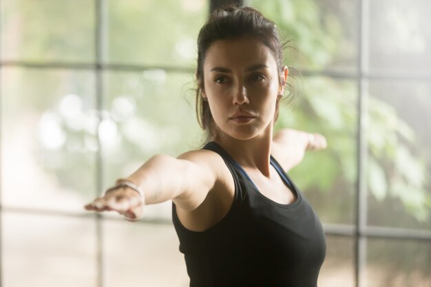 Young attractive woman in Virabhadrasana 2 pose