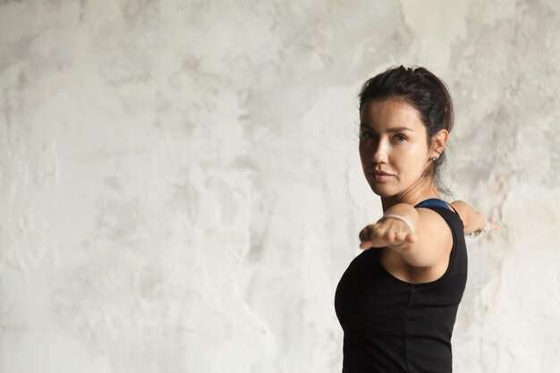 Young attractive woman in Virabhadrasana II pose