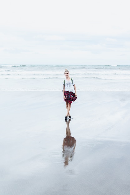 Free photo young attractive woman walking along the ocean shore on a sandy beach