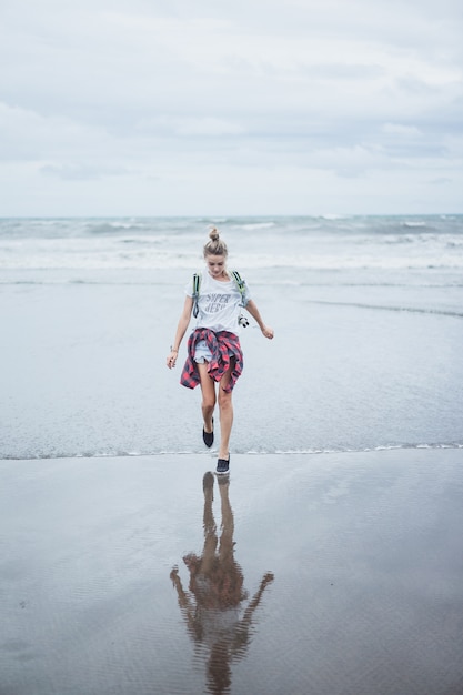 молодая привлекательная женщина, идущая вдоль берега океана на песчаном пляже
